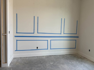 Blue tape marking the layout for decorative wall molding preparation by Royston Construction in Lafayette, LA