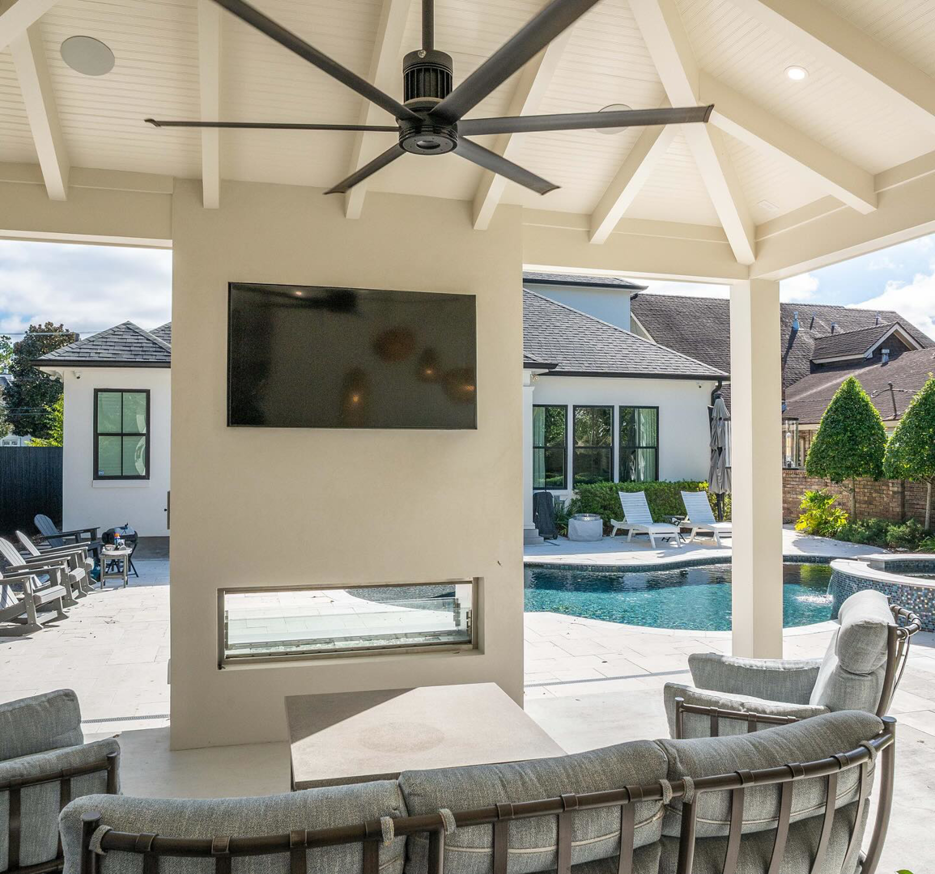 A wall-mounted TV and modern linear fireplace installed in an outdoor living area by FITZ Construction in Kenner, LA.