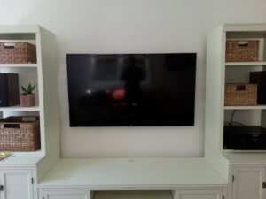 A wall-mounted television flanked by custom built-in shelving units by Barry's Handyman Service in San Diego, CA.