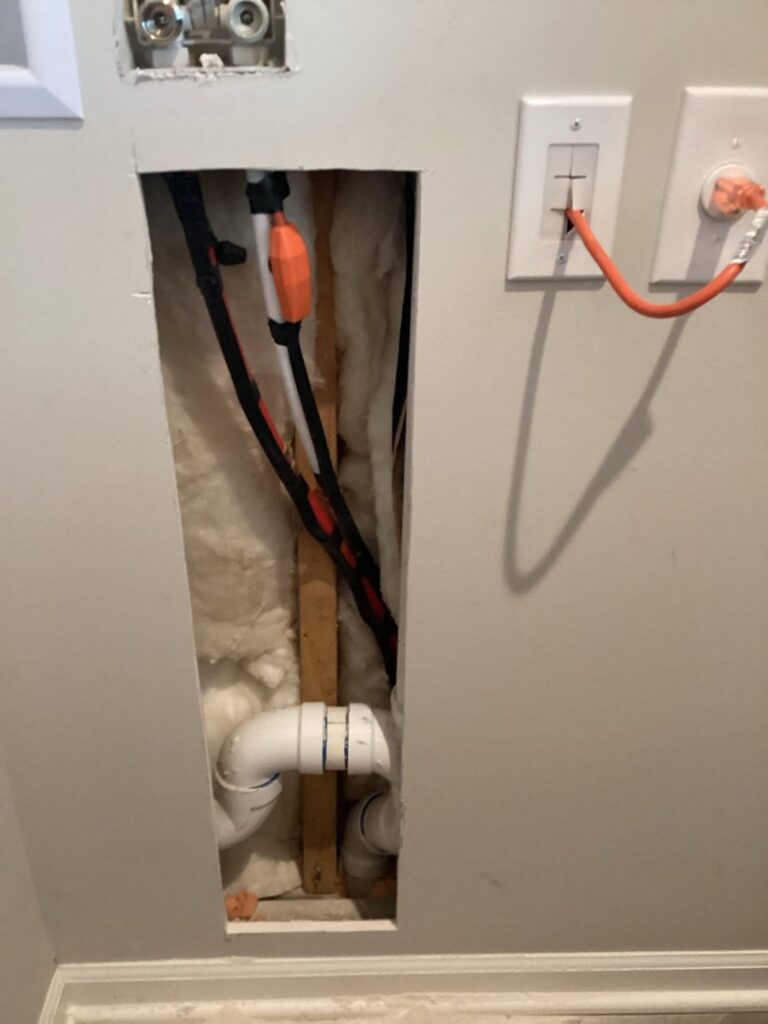 An opened wall revealing plumbing and electrical wiring, indicating a repair or installation in progress by Mr. Handyman of Olathe, Gardner in Olathe, KS.