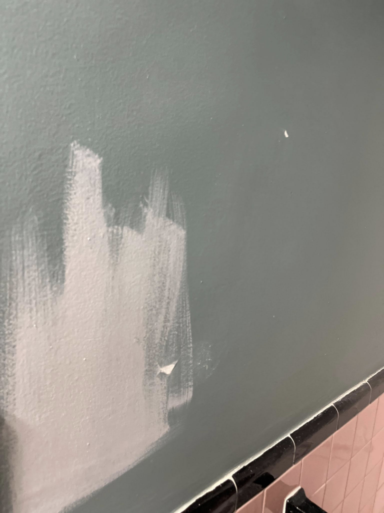 A wall showing white paint streaks over a darker color, indicating painting or touch-up work by Coach Rose Painting Team in Norfolk, VA.