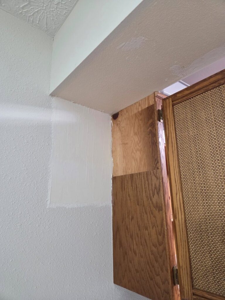 A wall patch with spackle and primer, indicating drywall repair in progress by Infinity Handyman in Anchorage, AK
