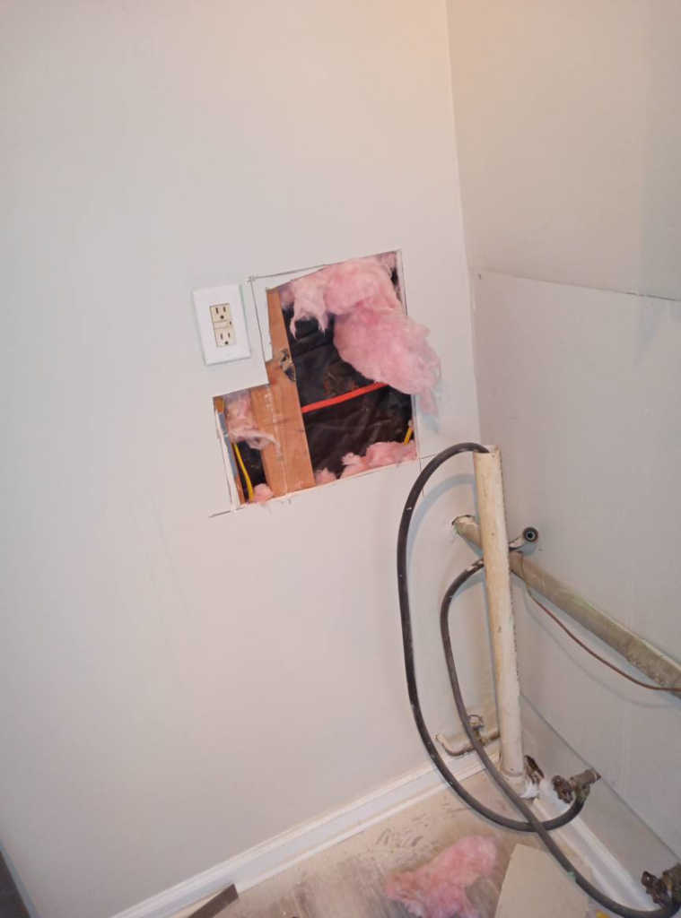 A wall with an open section revealing insulation and wiring, showing handyman repair by Charles and Drew Project Page in Detroit, MI.