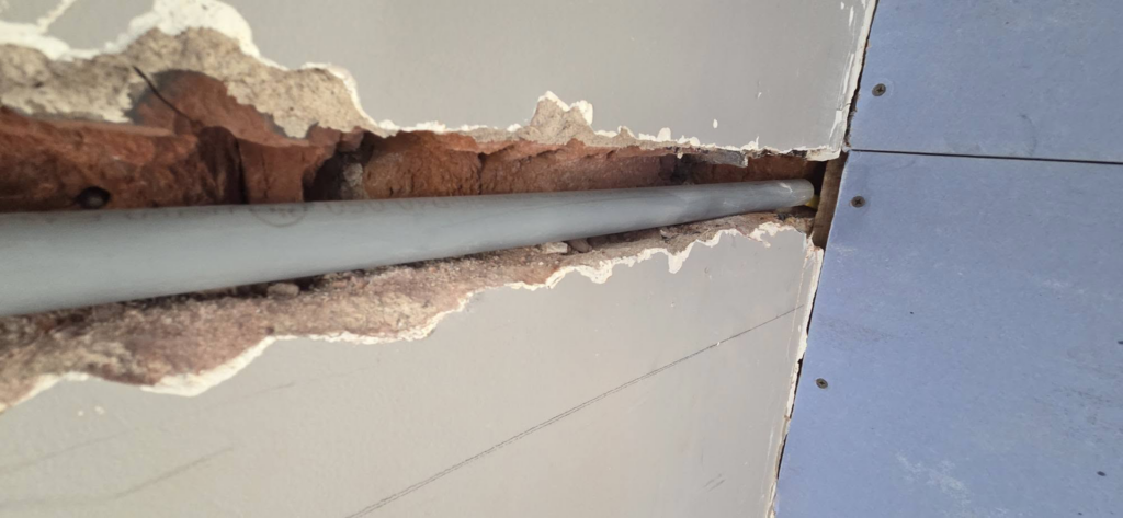 Wall repair showing a pipe installation behind drywall by AJ's Drywall & Finishing, LLC in St. Louis, MO.