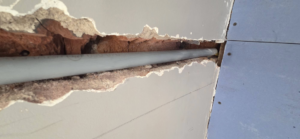 Wall repair showing a pipe installation behind drywall by AJ's Drywall & Finishing, LLC in St. Louis, MO.