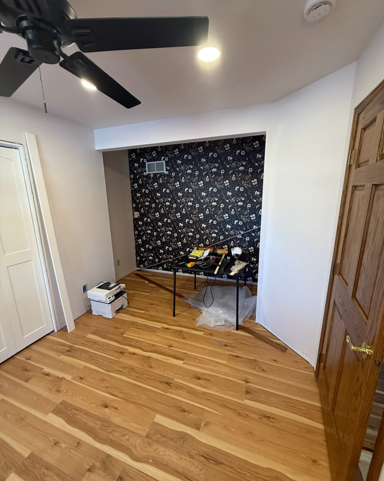 A room with new hardwood flooring and a newly installed floral wallpaper accent wall, with tools, by Fix Fast Flip, LLC in Plainfield, IL.