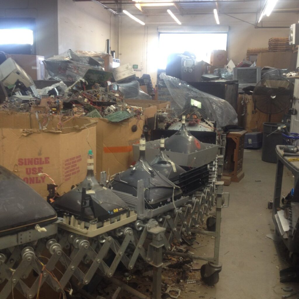 Warehouse filled with electronic waste, including old monitors, awaiting recycling by SES Secure E-Waste Solutions Inc. in San Diego, CA.