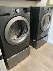 Newly installed washer and dryer appliances on pedestals in a laundry room by Prospective 1, LLC in Sparks, NV.