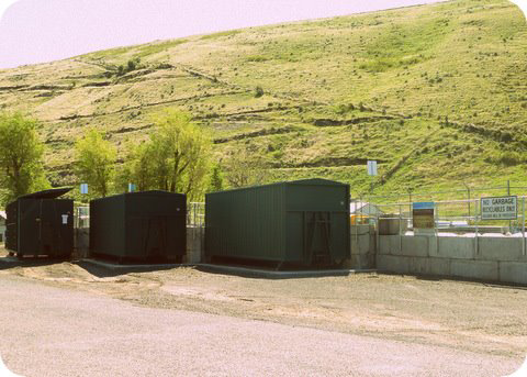 A waste and recycling collection facility with large green containers at Garfield County Recycling in Pomeroy, WA.