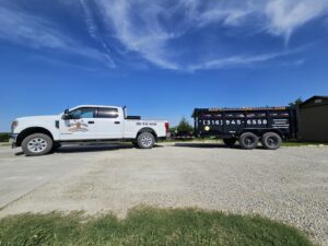A Waste Warrior branded truck pulling a dump trailer with junk removal services listed in Wichita, KS.