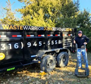 A Waste Warrior staff member giving a thumbs up next to a branded dump trailer with a hand truck in Wichita, KS.