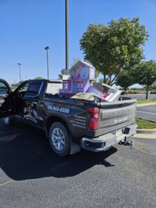 A Waste Warrior truck loaded with various items like a dollhouse and furniture for junk removal in Wichita, KS.