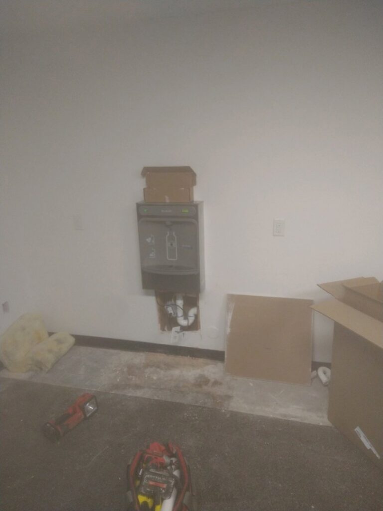 A wall-mounted water cooler and bottle filler installation with exposed plumbing and electrical work by Mr. Affordable LLC in Denver, CO.