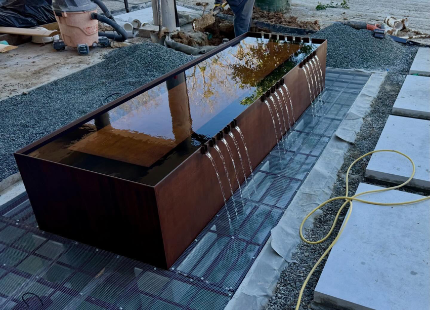Modern water feature under construction by First Class Pools & Spas, showcasing general contractor work in Sachse, TX.