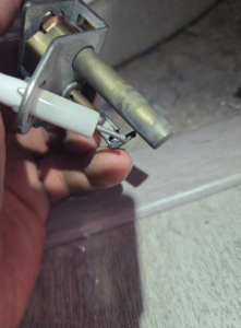 A close-up of a hand holding a water heater igniter, indicating repair work by DMax solutions in Fernley, NV.