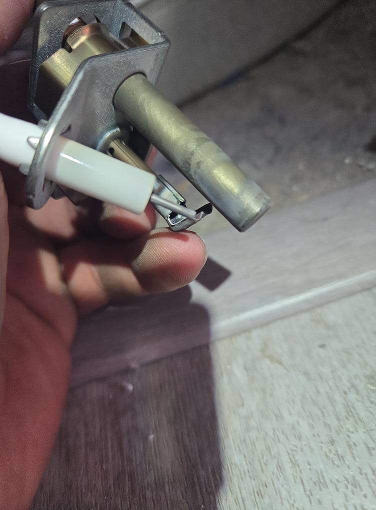 A close-up of a hand holding a water heater igniter, indicating repair work by DMax solutions in Fernley, NV.