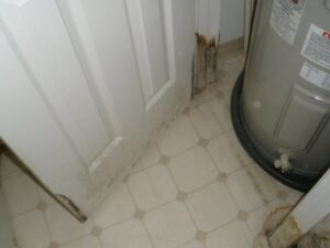 Water heater area showing mold and water damage on the wall and floor, needing restoration by Paul Davis Restoration of Charlotte, NC.