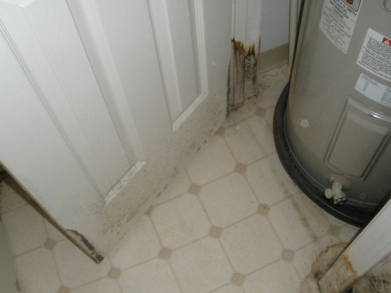 Water heater area showing mold and water damage on the wall and floor, needing restoration by Paul Davis Restoration of Charlotte, NC.
