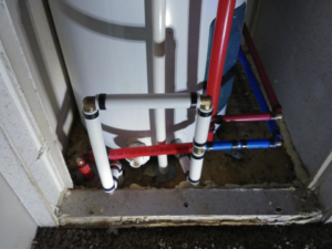 Detailed view of PEX plumbing connections at the base of a water heater by Home Solutions of Kansas City in Kansas City, MO