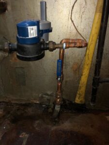 A water meter and copper pipe installation in a utility area by Hessville Plumbing in Hammond, IN.
