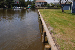 A well-maintained wooden seawall protecting a grassy waterfront property, installed by Spence Marine Construction Inc. in Virginia Beach, VA.