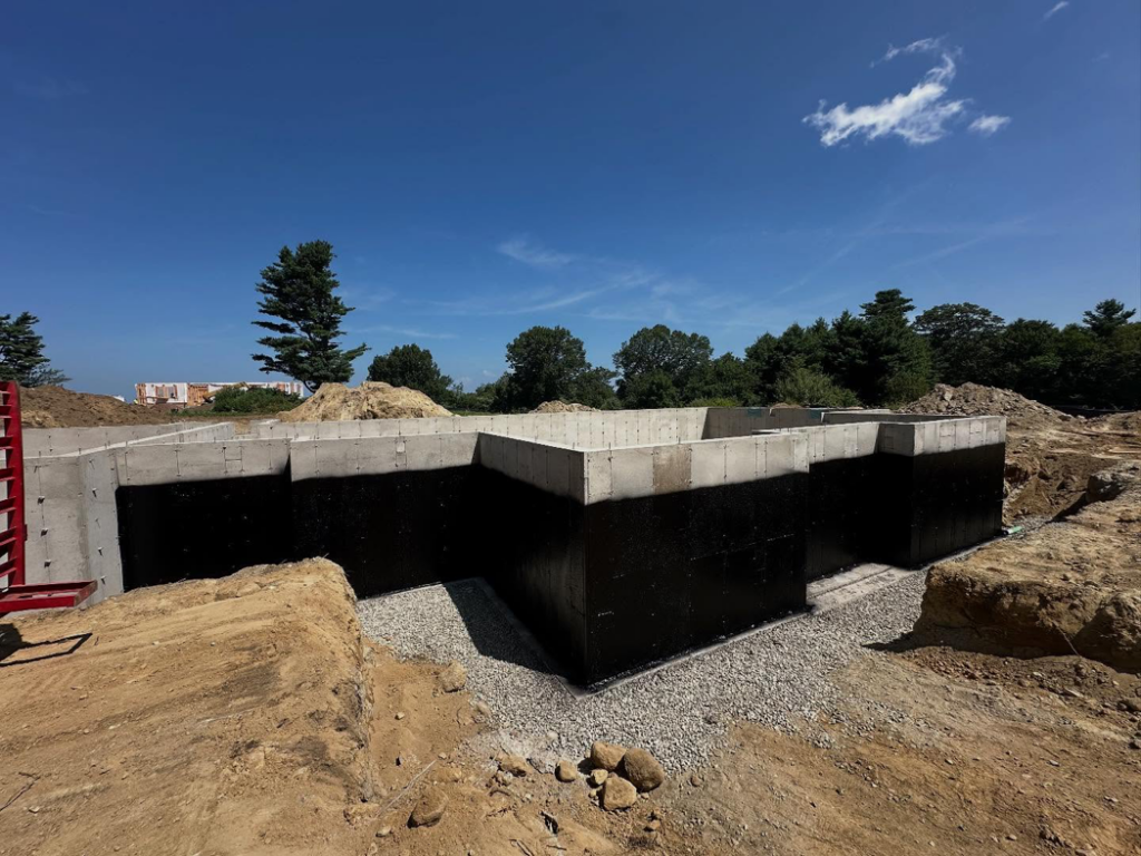 A waterproofed concrete foundation surrounded by gravel, completed by ProSeal Waterproofing in Naugatuck, CT.