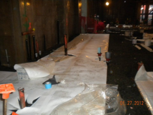 Installation of waterproofing membrane on an interior construction site floor by Crown Waterproofing Inc. Mount Vernon, NY.