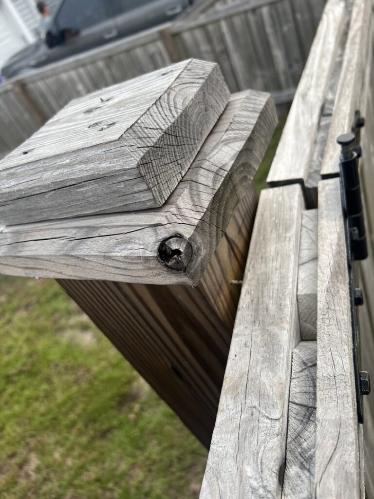 A close-up view of a weathered wooden fence post and gate hinge, showing potential repair or maintenance work by Frontline Fencing LLC in Summerville, SC.