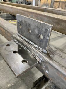 A close-up of a metal beam with a newly welded plate and bracket, demonstrating precision welding by Jeremy's Welding & Handyman in West Jordan, UT.