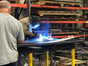 A welder in protective gear fabricating a metal structure at KCR Welding, INC. in Moore, OK.