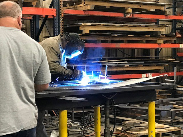 A welder in protective gear fabricating a metal structure at KCR Welding, INC. in Moore, OK.