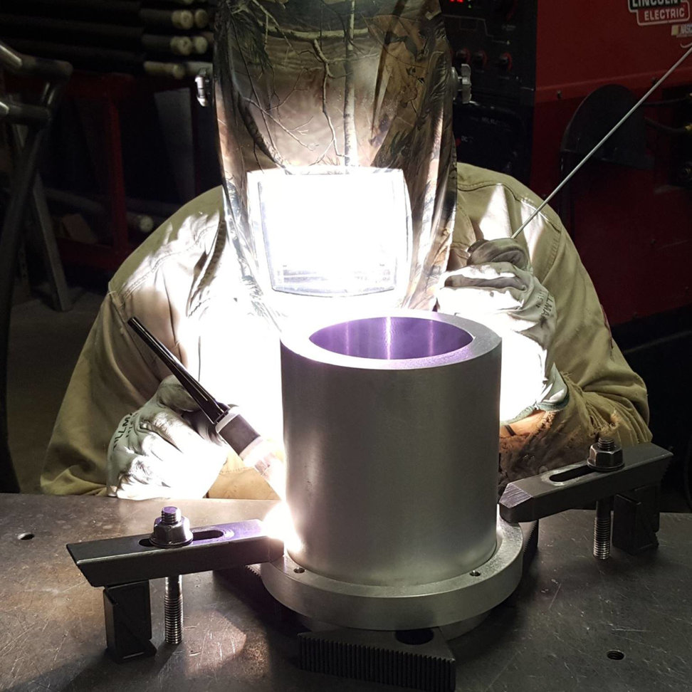 A skilled welder in protective gear working on a metal cylinder at KCR Welding, INC. in Moore, OK.