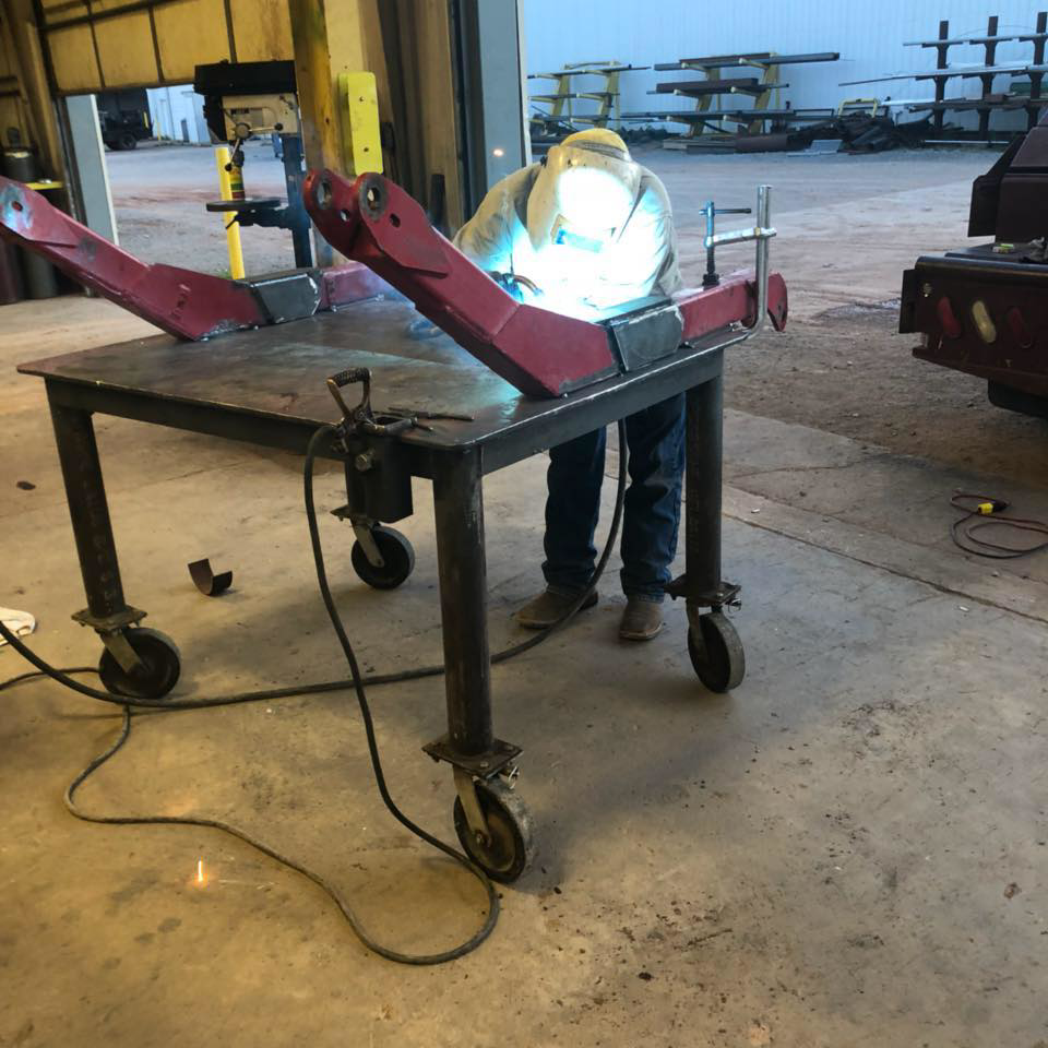 A skilled welder performing metal fabrication on a workbench at Silver Services in Enid, OK.