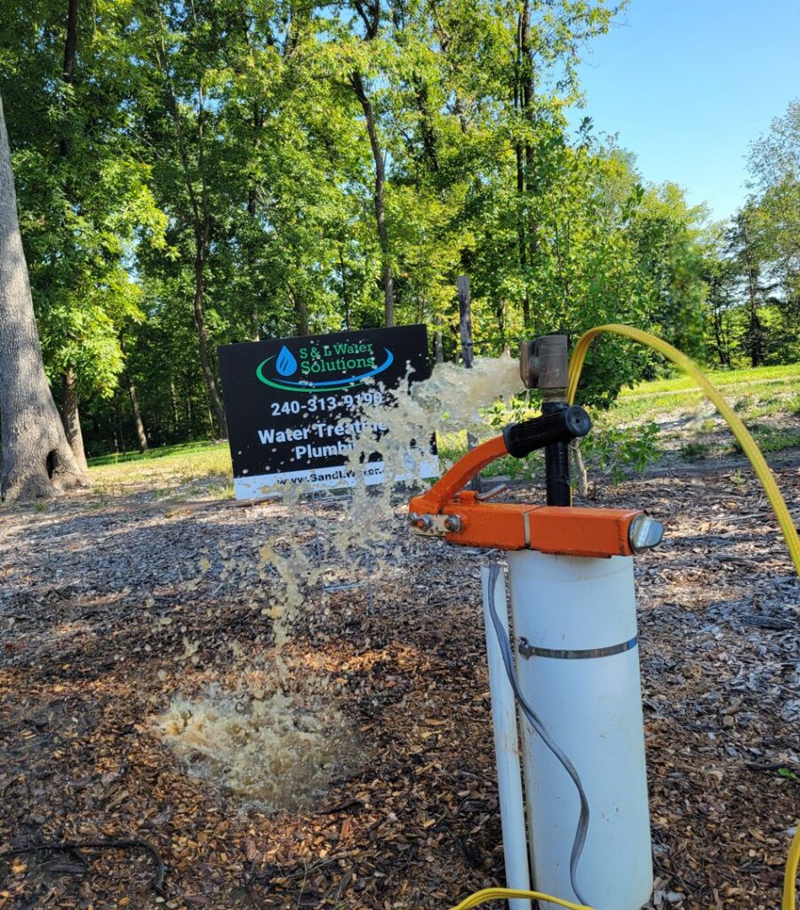 Well pump testing with muddy water spraying from the wellhead by S & L Water Solutions in Hagerstown, MD.