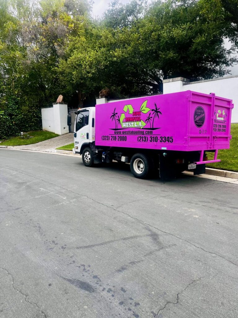 A pink West LA Hauling junk removal truck parked on a residential street in Los Angeles, CA.