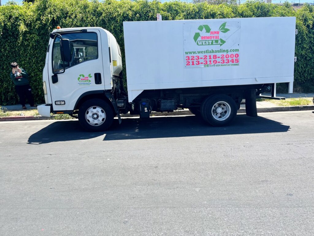 A white junk removal truck with West LA Hauling branding parked on a street in Los Angeles, CA.