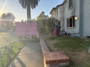 A West LA Hauling worker loading a large amount of junk into a pink removal truck in Los Angeles, CA.