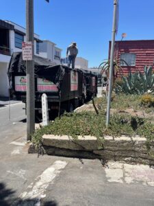 A West LA Hauling worker securing a tarp over a loaded junk removal truck in Los Angeles, CA.