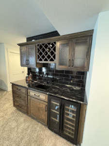 A newly installed wet bar with dark wood cabinets and black granite countertop by McWilliams & Company in Ketchum, ID.