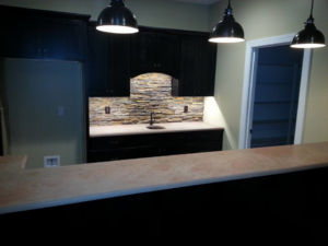 A custom wet bar installation with dark cabinets and a stacked stone backsplash by Cliff's Construction in Richmond, VA.
