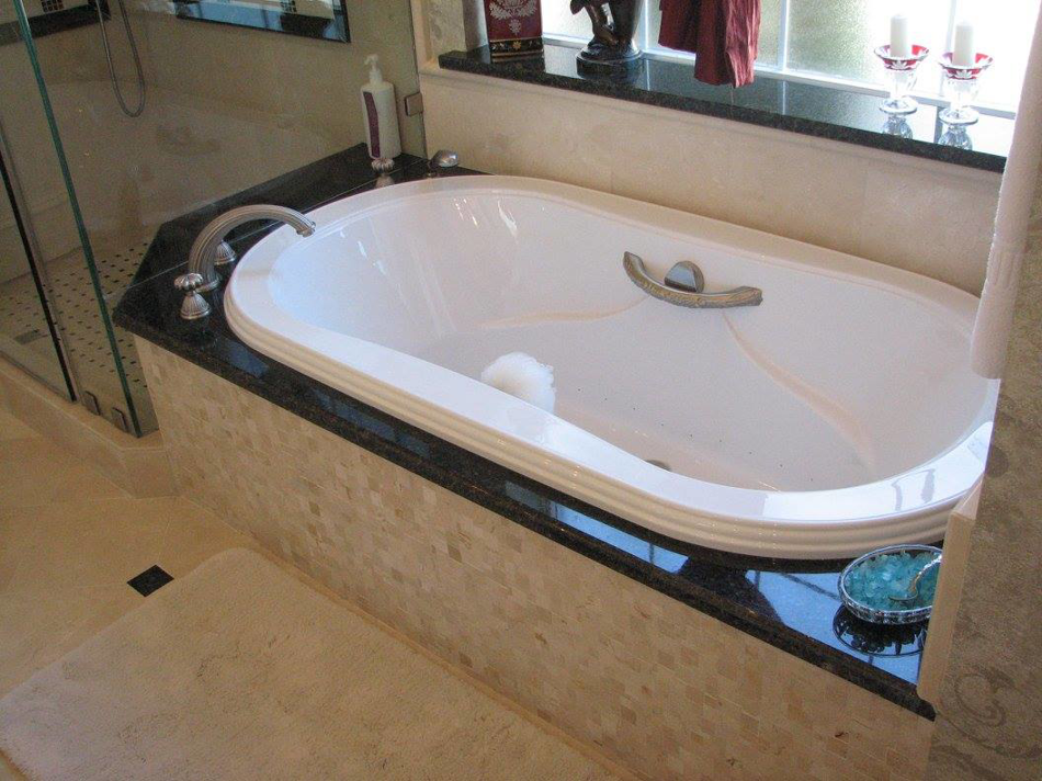 A newly installed white bathtub with a sleek black granite surround by Metro Contractors & Supply, Inc. in Norman, OK