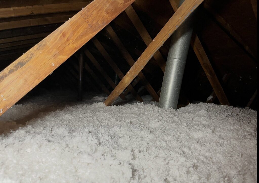 Attic space with white blown-in insulation and wooden rafters installed by ADDICT INSULATION, LLC in St. Charles, MO
