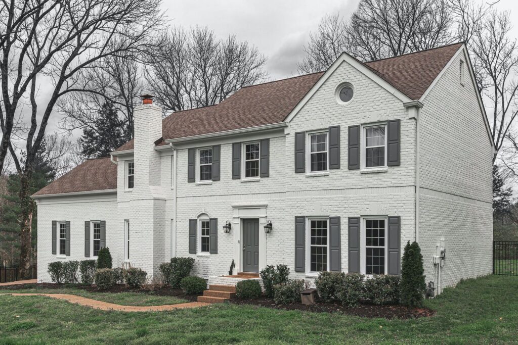 A white brick house with dark shutters and trim, painted by Harpeth Painting, LLC. in Nashville, TN.