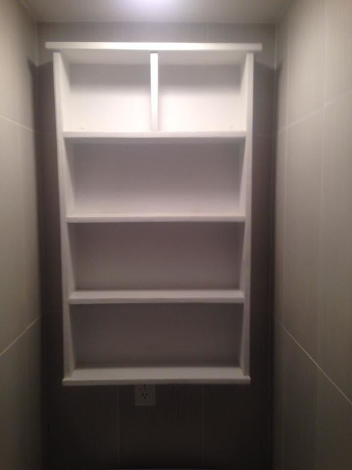 A white built-in shelf unit installed in a tiled bathroom by J Development in Pittsburgh, PA.