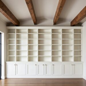 White built-in bookshelves extending across a wall with exposed wooden ceiling beams by Corkery Customs & Remodeling LLC in Philadelphia, PA