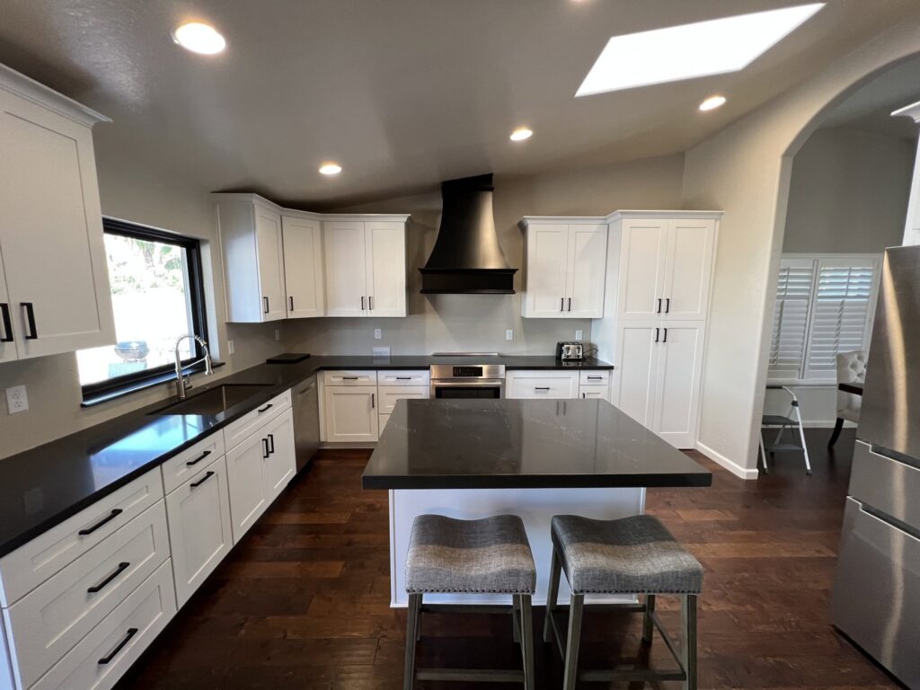 A newly installed kitchen featuring white cabinets and black countertops by Dahlman Construction in San Tan Valley, AZ.