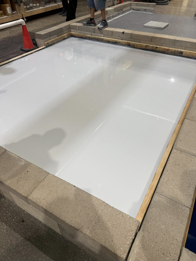 White epoxy floor installation sample by CC&J Construction, INC in Bernville, PA, framed by concrete blocks.