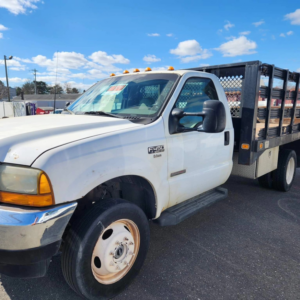 A white Ford F450 flatbed truck with high metal cage sides, used for junk removal services by Tri-State Carting, Inc in Bayville, NJ.