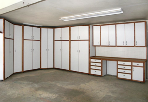 A white garage cabinet system with brown trim, a workbench, drawers, and pegboard installed by NW Garage Cabinet Company in Ridgefield, WA.