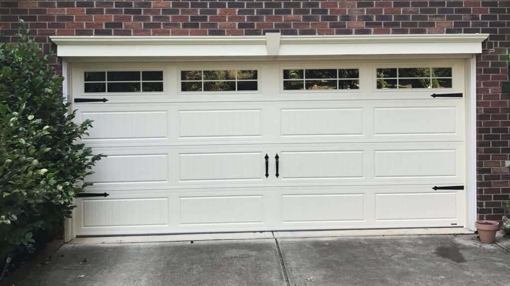 A white garage door with decorative hardware on a brick house by Total Garage Works in Indian Trail, NC.